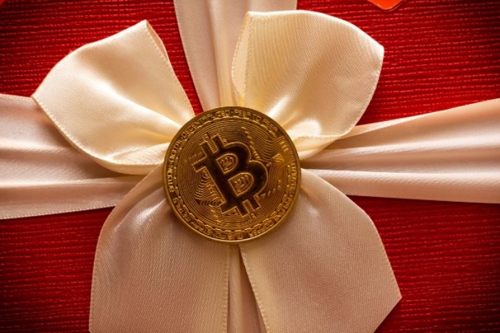 red gift package wrapped with yellow ribbon and bitcoin gold coin