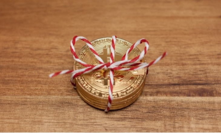 stack of gold coins with bitcoin symbol wrapped with red and white string